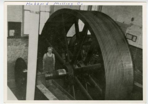 Man next to large, metal milling wheel