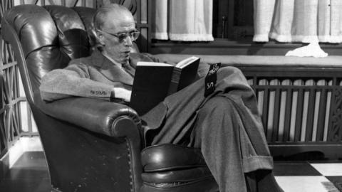 Sinclair Lewis reading a book in his chair
