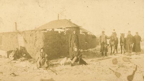 Sod house with people and horses