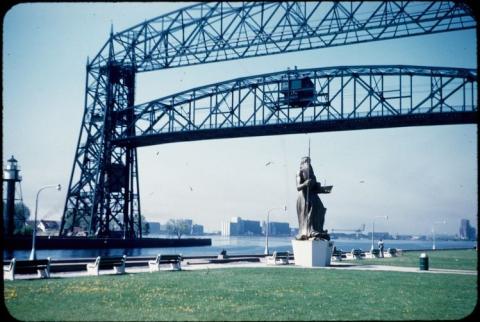 Neptune statue holding trident on lawn in front of lift bridge