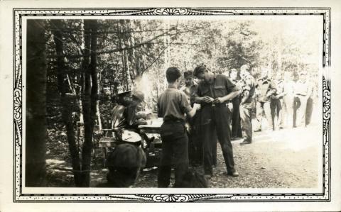 Men lining up to receive paychecks in the woods