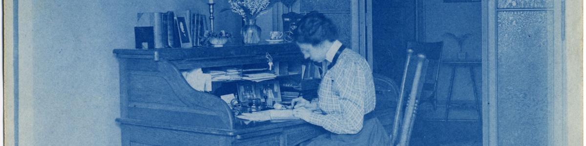 Woman seated at a desk writing on paper